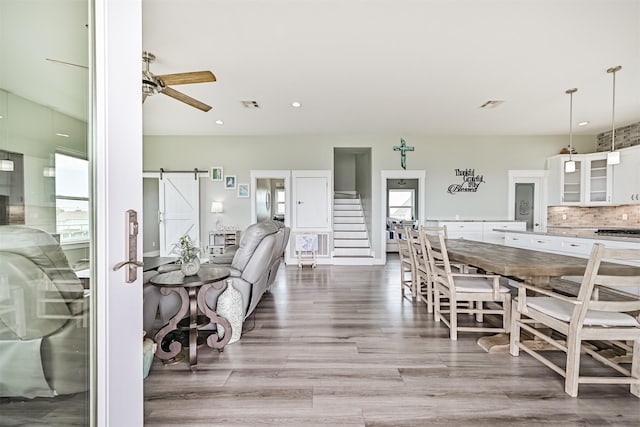 16631 Jean Lafitte Rd, Galveston, TX 77554 - dining room with a barn door, wood finished floors, ceiling fan, stairway, and plenty of natural light