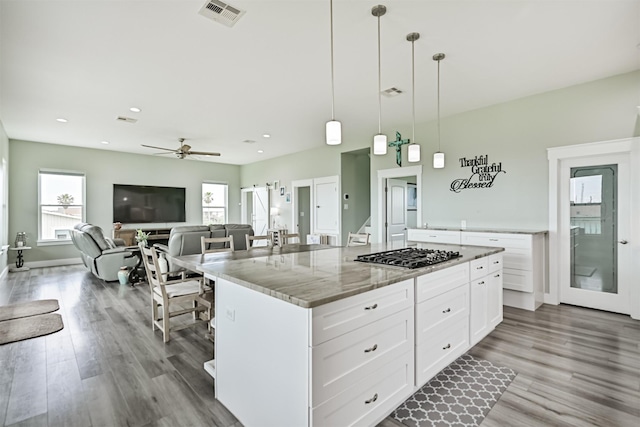 16631 Jean Lafitte Rd, Galveston, TX 77554 - kitchen with stainless steel gas stovetop, healthy amount of natural light, wood finished floors, white cabinets, and recessed lighting