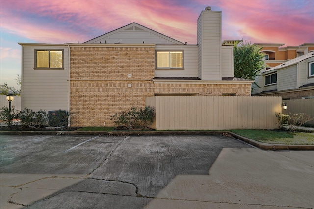 1829 Augusta Dr Unit 33, Houston, TX 77057 - property exterior at dusk with brick siding, a chimney, and uncovered parking