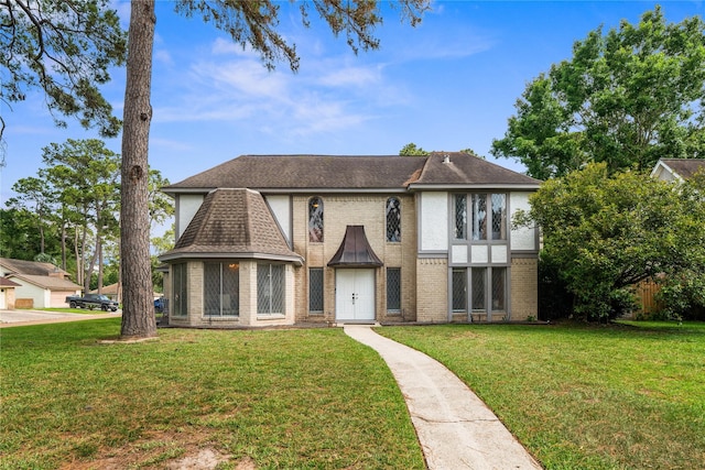 view of front of property with a front yard, brick siding, and a shingled roof