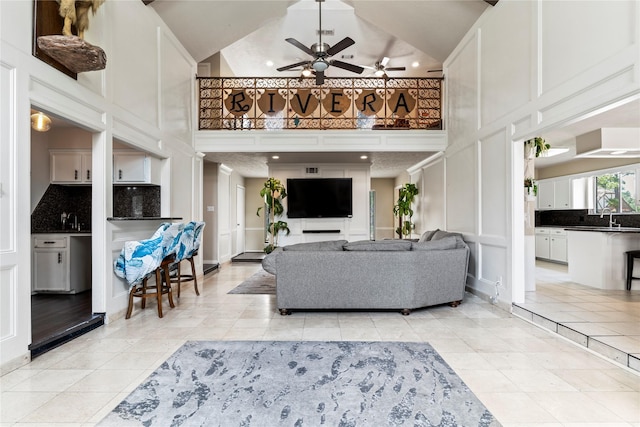 living room featuring a high ceiling, a decorative wall, ceiling fan, recessed lighting, and light tile patterned floors