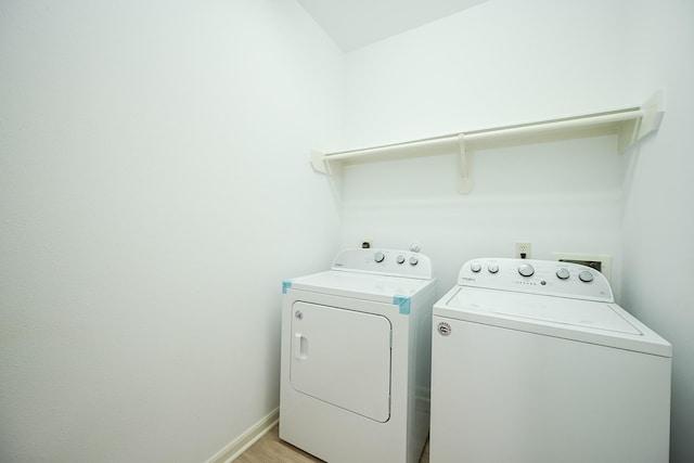laundry room with washing machine and dryer, baseboards, and light wood finished floors