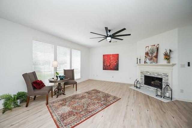 living area with wood finished floors, a ceiling fan, a tile fireplace, and baseboards