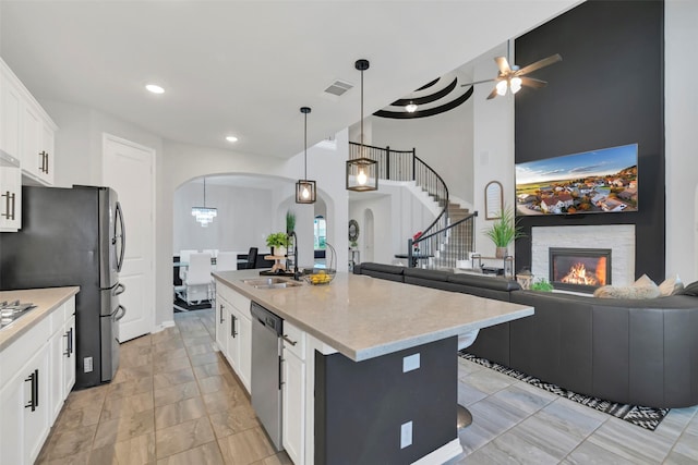 15606 Upper Lochton Dr, Humble, TX 77346 - kitchen featuring a sink, stainless steel appliances, arched walkways, ceiling fan, and white cabinets