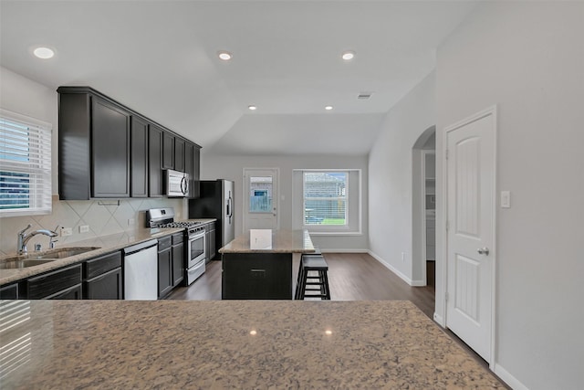 3213 Hatteras Dr, Texas City, TX 77591 - kitchen with stainless steel appliances, a sink, a breakfast bar, arched walkways, and light stone counters