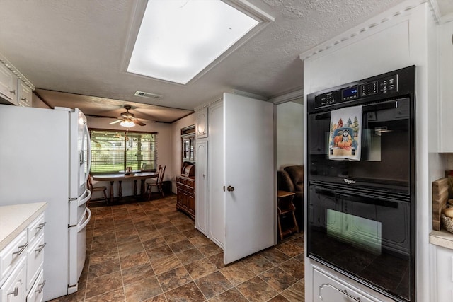 229 Willowbend St, Huntsville, TX 77320 - kitchen with freestanding refrigerator, white cabinetry, light countertops, a ceiling fan, and stone finish flooring