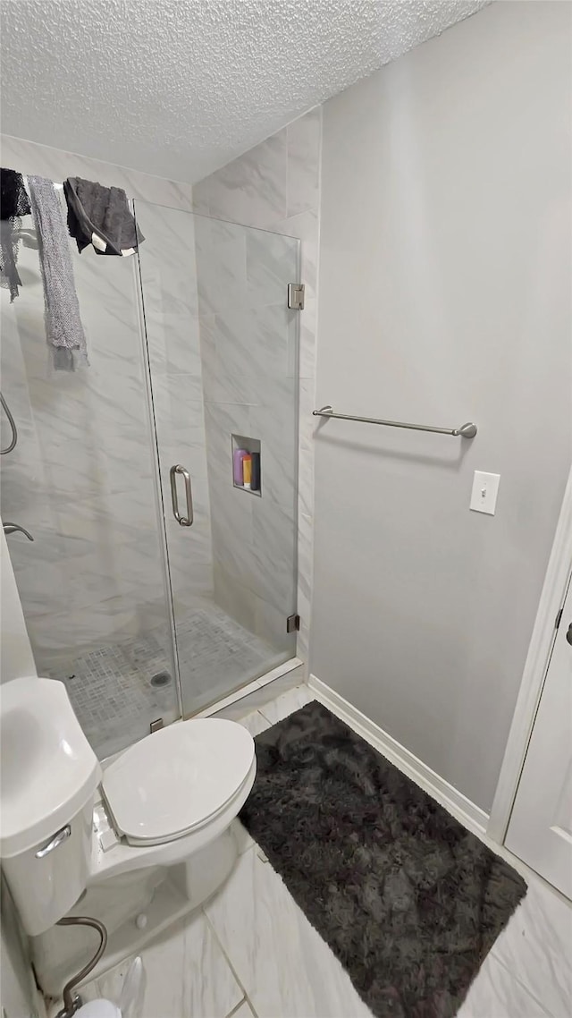 2263 Triway Ln, Houston, TX 77043 - bathroom with a textured ceiling, toilet, a shower stall, marble finish floors, and baseboards