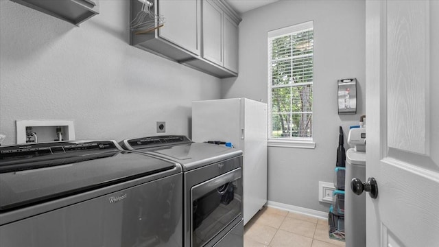 13402 Layton Castle Ln, Cypress, TX 77429 - washroom with washer and clothes dryer, cabinet space, healthy amount of natural light, and light tile patterned flooring