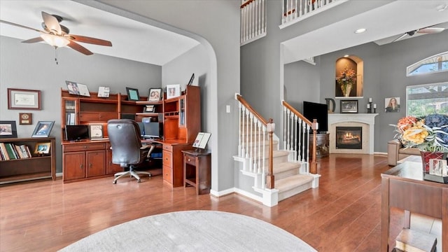 13402 Layton Castle Ln, Cypress, TX 77429 - office with a ceiling fan, a towering ceiling, wood finished floors, a glass covered fireplace, and baseboards