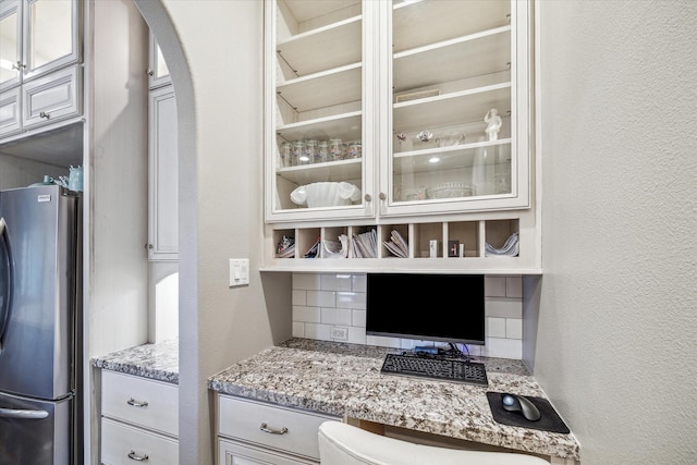 32319 Tall Oaks Way, Magnolia, TX 77354 - kitchen with freestanding refrigerator, backsplash, arched walkways, glass insert cabinets, and a textured wall