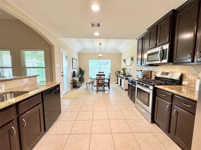969 Gowan Dr, Conroe, TX 77301 - kitchen featuring appliances with stainless steel finishes, backsplash, light tile patterned flooring, lofted ceiling, and recessed lighting