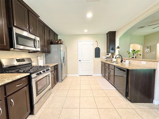 969 Gowan Dr, Conroe, TX 77301 - kitchen with appliances with stainless steel finishes, backsplash, dark brown cabinetry, light stone counters, and recessed lighting