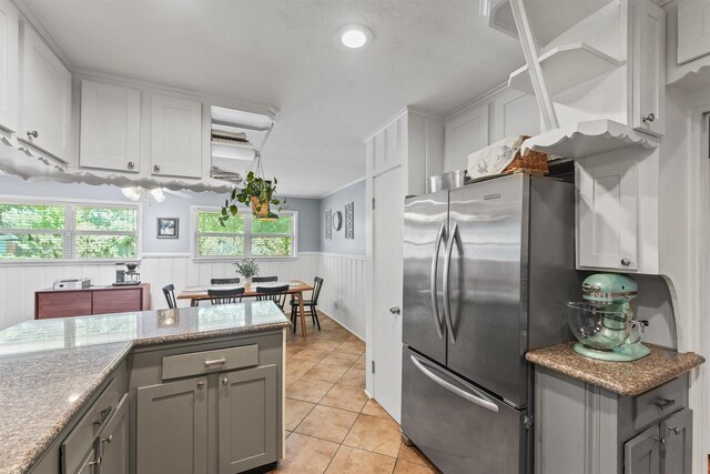 10438 Brinwood Dr, Houston, TX 77043 - kitchen with freestanding refrigerator, gray cabinetry, wainscoting, light tile patterned floors, and white cabinets