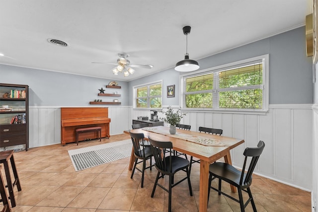 10438 Brinwood Dr, Houston, TX 77043 - dining space featuring wainscoting, light tile patterned floors, a ceiling fan, a decorative wall, and crown molding
