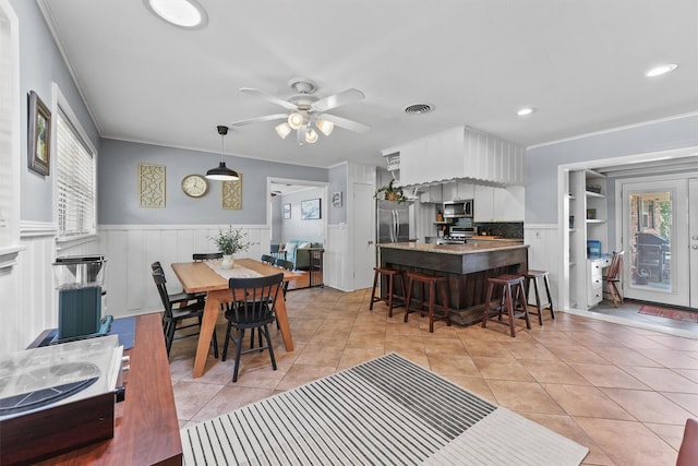10438 Brinwood Dr, Houston, TX 77043 - dining space with a wainscoted wall, light tile patterned flooring, crown molding, recessed lighting, and ceiling fan