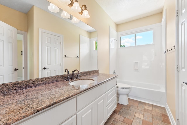 bathroom with toilet, stone tile floors, vanity, shower / tub combination, and baseboards