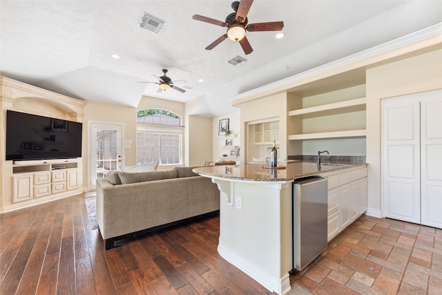 kitchen featuring a sink, open shelves, fridge, ceiling fan, and stone counters