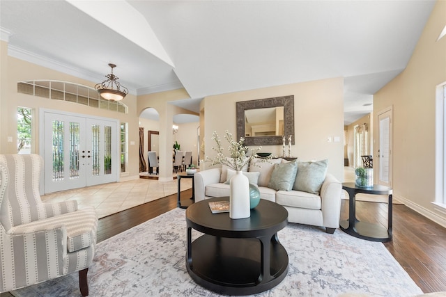 living room featuring hardwood / wood-style flooring, french doors, ornamental molding, arched walkways, and baseboards