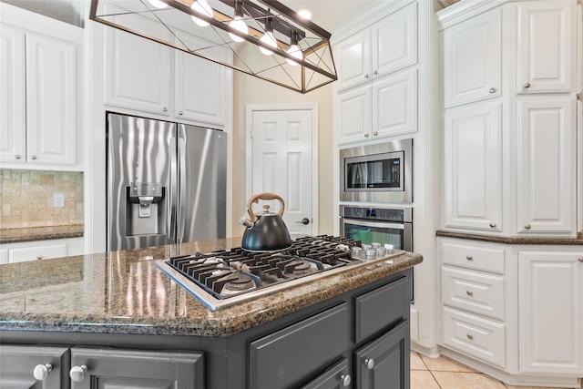 kitchen featuring stainless steel appliances, gray cabinetry, white cabinets, and dark stone counters