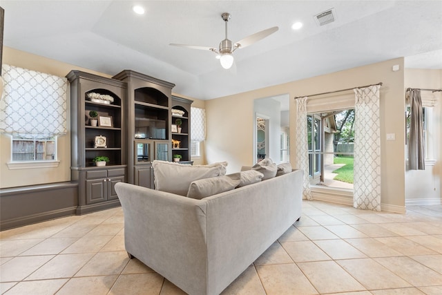 living area featuring ceiling fan, light tile patterned floors, vaulted ceiling, and baseboards
