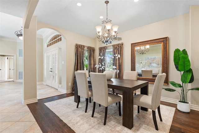 dining room featuring a chandelier, arched walkways, light wood-style floors, recessed lighting, and baseboards