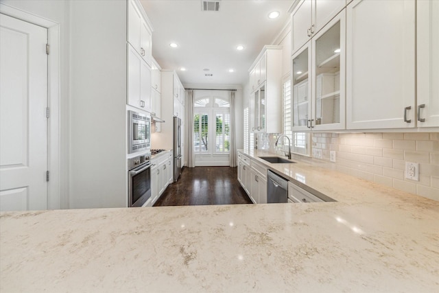 1206 Lake Pointe Pkwy, Sugar Land, TX 77478 - kitchen featuring stainless steel appliances, a sink, light stone counters, dark wood-style floors, and glass insert cabinets