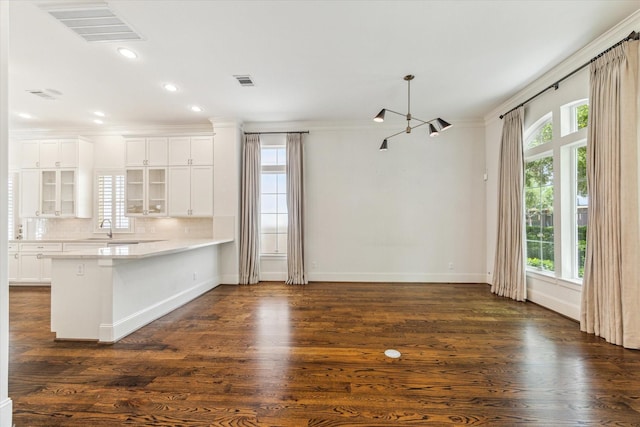 1206 Lake Pointe Pkwy, Sugar Land, TX 77478 - kitchen featuring glass insert cabinets, crown molding, a peninsula, baseboards, and white cabinetry