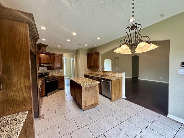 305 Tyler Dr, Bridge City, TX 77630 - kitchen featuring arched walkways, stainless steel appliances, tasteful backsplash, a peninsula, and a textured ceiling