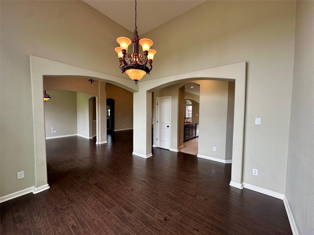 305 Tyler Dr, Bridge City, TX 77630 - spare room featuring arched walkways, a chandelier, dark wood-type flooring, baseboards, and high vaulted ceiling
