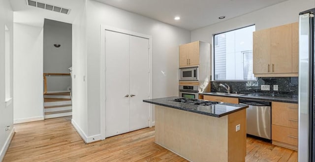 730 Ruthven, Houston, TX 77019 - kitchen featuring stainless steel appliances, a sink, light brown cabinets, a center island, and light wood-style floors