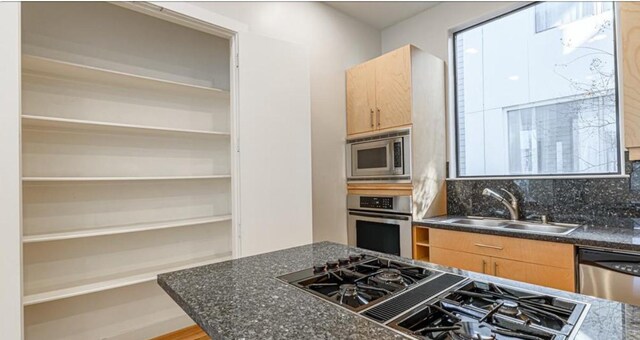 730 Ruthven, Houston, TX 77019 - kitchen featuring stainless steel appliances, a sink, light brown cabinets, and backsplash