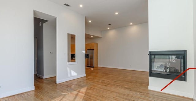 730 Ruthven, Houston, TX 77019 - unfurnished living room featuring light wood finished floors, a multi sided fireplace, recessed lighting, and baseboards
