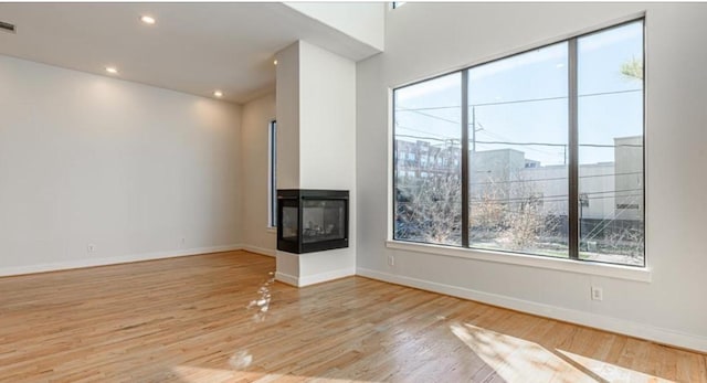 730 Ruthven, Houston, TX 77019 - unfurnished living room featuring light wood-type flooring, a multi sided fireplace, baseboards, and recessed lighting