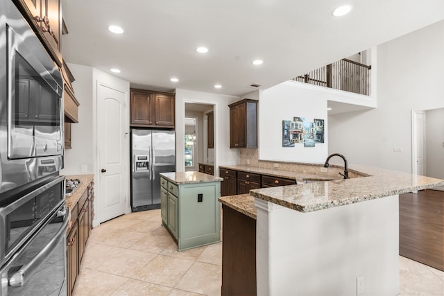 kitchen featuring stainless steel appliances, a peninsula, a sink, a kitchen island, and recessed lighting