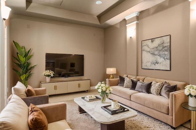 living room featuring decorative columns and a tray ceiling