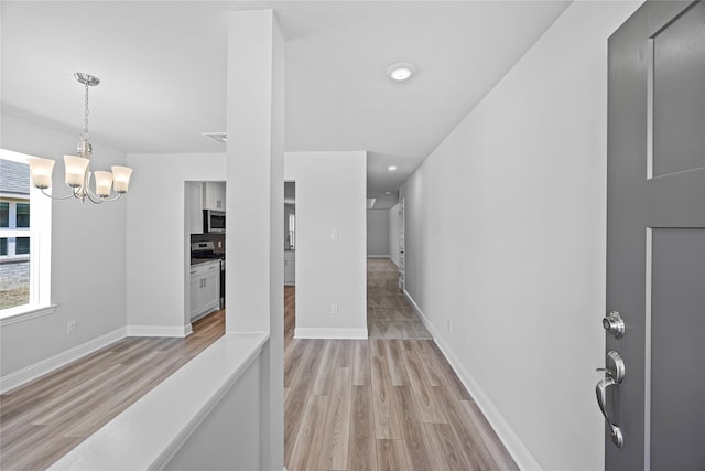 20068 Swinley Forest Dr, Cleveland, TX 77327 - hallway featuring light wood-type flooring, a chandelier, and baseboards