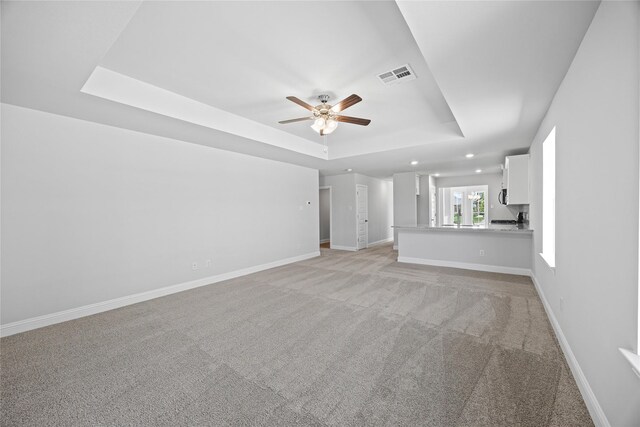 20068 Swinley Forest Dr, Cleveland, TX 77327 - unfurnished living room with a raised ceiling, light carpet, ceiling fan, baseboards, and recessed lighting