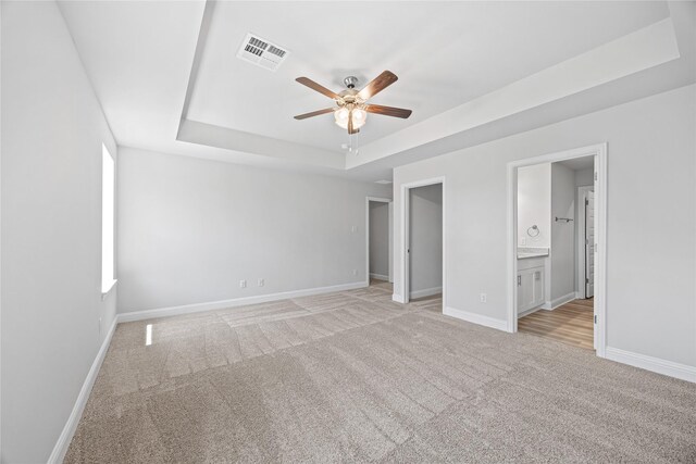 20068 Swinley Forest Dr, Cleveland, TX 77327 - unfurnished bedroom featuring a tray ceiling, light colored carpet, baseboards, a walk in closet, and connected bathroom