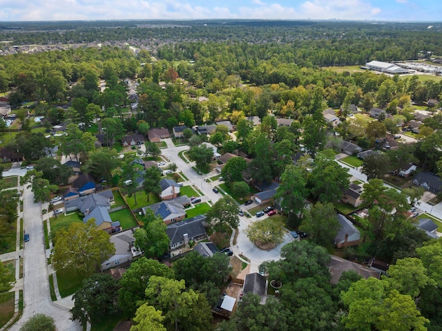 aerial view of property and surrounding area featuring a forest and nearby suburban area