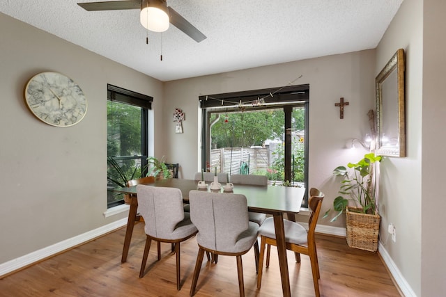 dining room with wood finished floors, a textured ceiling, baseboards, and a ceiling fan