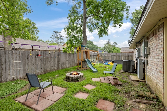 view of yard featuring a fire pit, central AC, and a playground