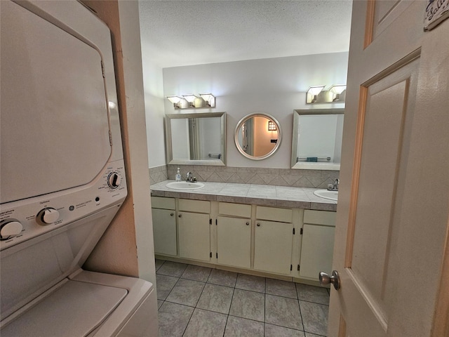 1100 Augusta Dr Unit 42, Houston, TX 77057 - bathroom featuring stacked washing machine and dryer, tile patterned flooring, double vanity, and tasteful backsplash