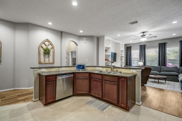 kitchen featuring dishwasher, a sink, arched walkways, open floor plan, and recessed lighting