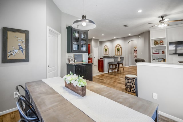 dining space with baseboards, wood finished floors, ceiling fan, recessed lighting, and arched walkways
