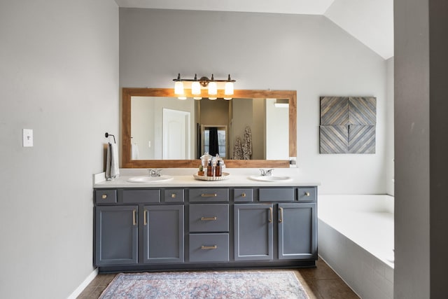 full bath with tile patterned floors, lofted ceiling, double vanity, and a garden tub