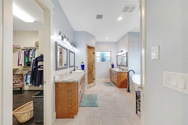 5523 Harvest Oak Landing Dr, Spring, TX 77386 - bathroom with two vanities, a tile shower, a spacious closet, tile patterned flooring, and baseboards