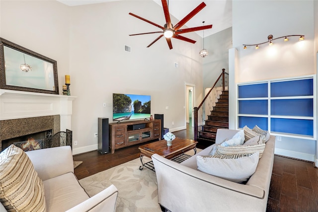5523 Harvest Oak Landing Dr, Spring, TX 77386 - living room with high vaulted ceiling, ceiling fan, a warm lit fireplace, wood finished floors, and stairway
