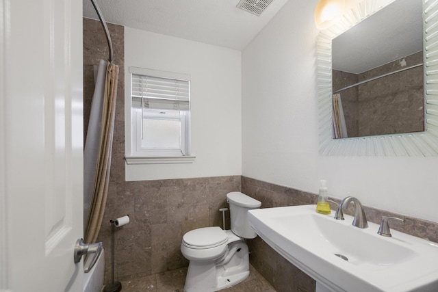 17310 Chaseloch St, Spring, TX 77379 - bathroom with a sink, tile walls, toilet, wainscoting, and a shower with shower curtain
