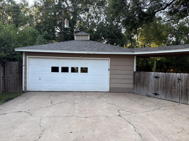 garage featuring fence and concrete driveway