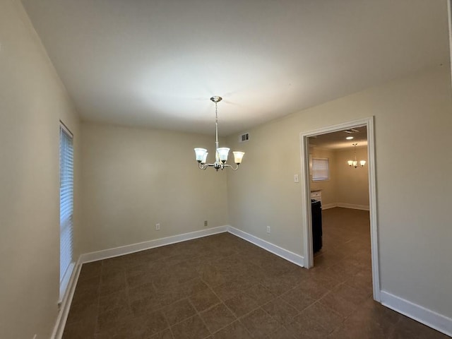 spare room featuring a chandelier and baseboards